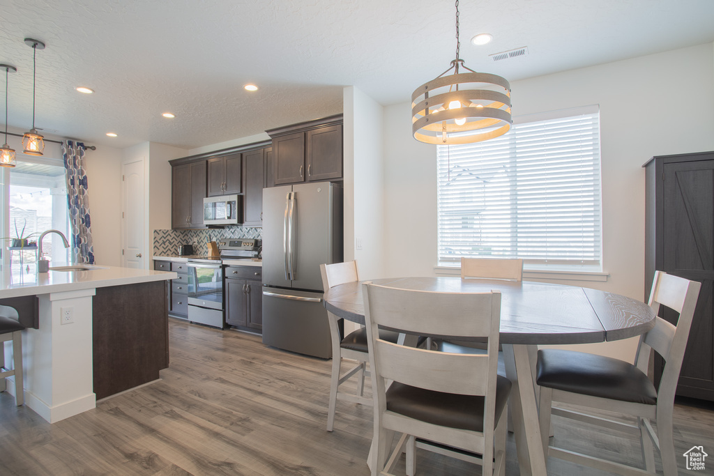 Kitchen with backsplash, stainless steel appliances, pendant lighting, and a breakfast bar