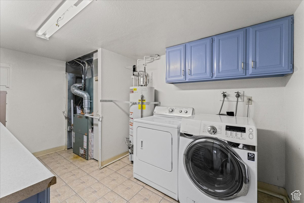 Washroom with light tile floors, cabinets, water heater, and separate washer and dryer