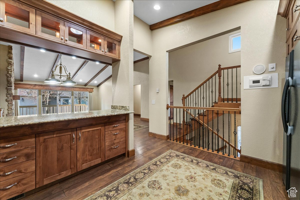 Kitchen featuring high vaulted ceiling, dark hardwood / wood-style flooring, light stone countertops, and beamed ceiling