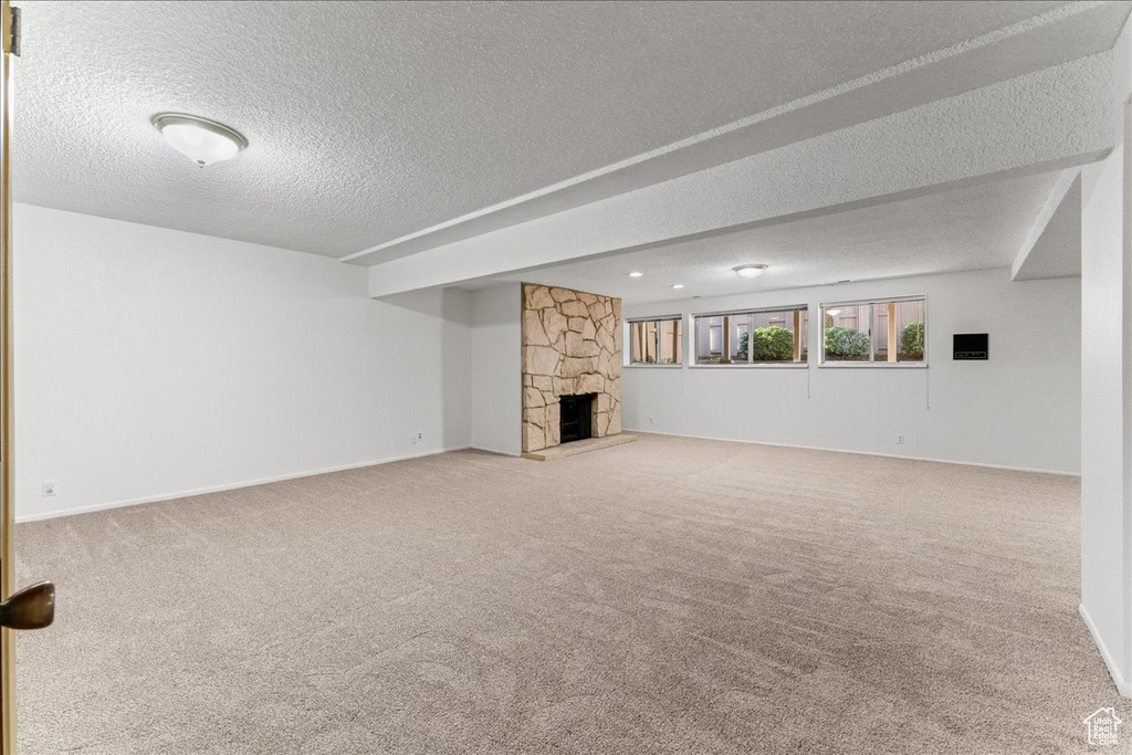 Unfurnished living room with light carpet, a textured ceiling, and a fireplace