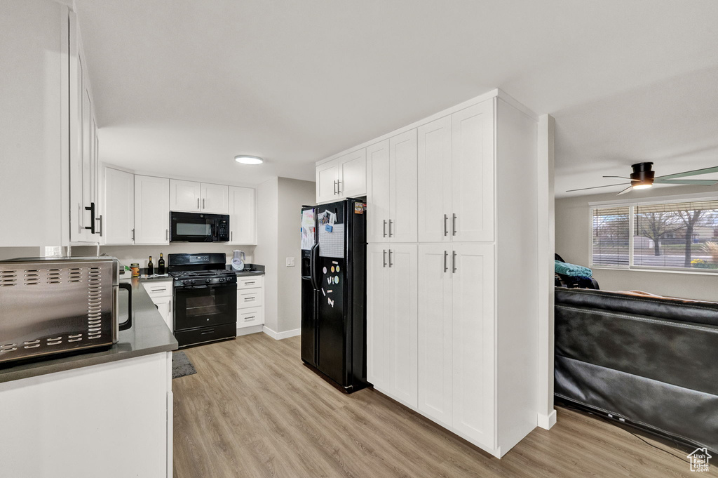 Kitchen with light hardwood / wood-style flooring, ceiling fan, white cabinetry, and black appliances
