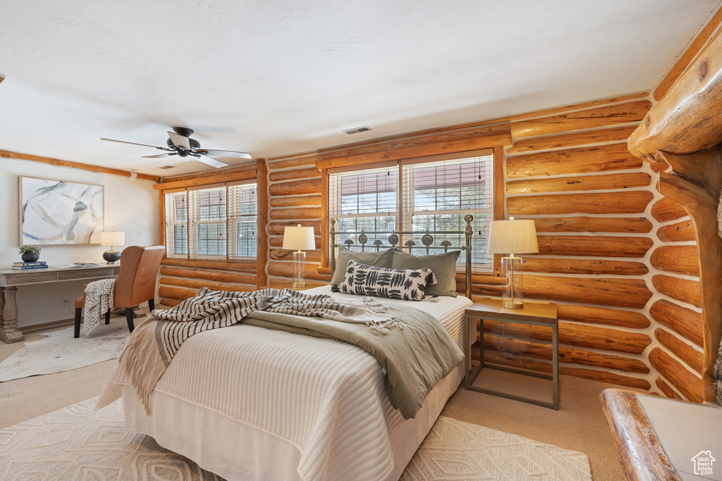 Bedroom with log walls, light colored carpet, and ceiling fan