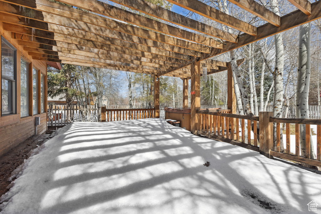 Snow covered deck featuring a pergola