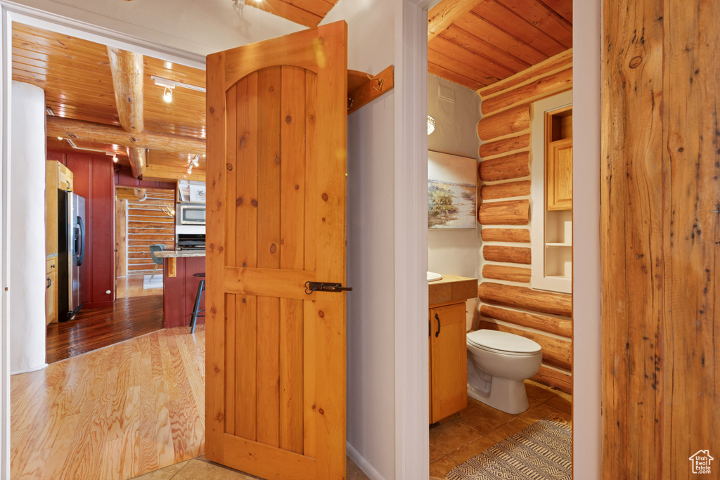 Bathroom featuring vanity, hardwood / wood-style floors, log walls, toilet, and wood ceiling