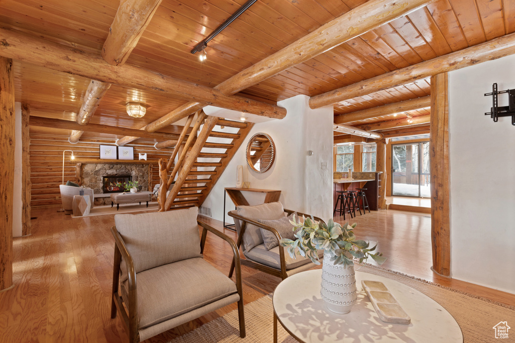 Living room featuring log walls, light hardwood / wood-style flooring, wood ceiling, and track lighting