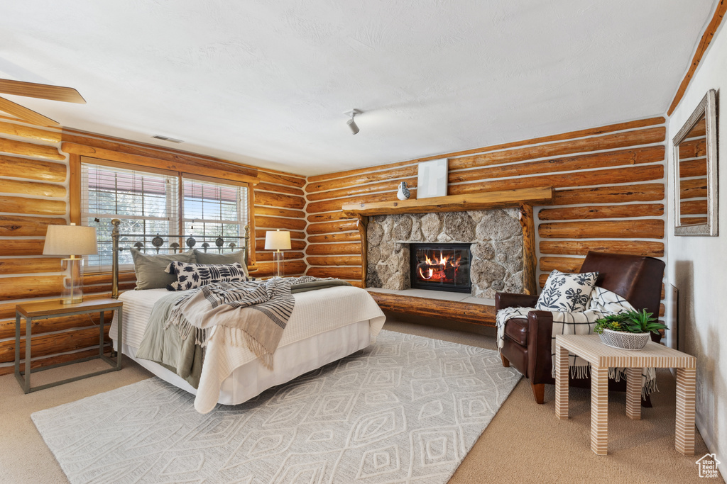 Carpeted bedroom featuring log walls and a fireplace