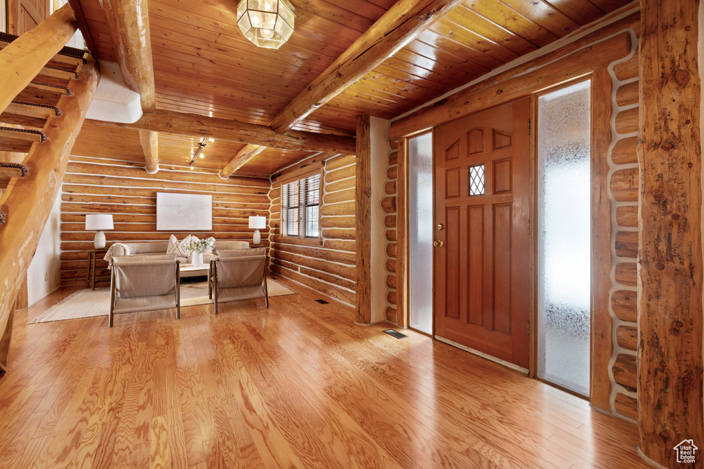 Entrance foyer with beam ceiling, log walls, light hardwood / wood-style floors, and wooden ceiling