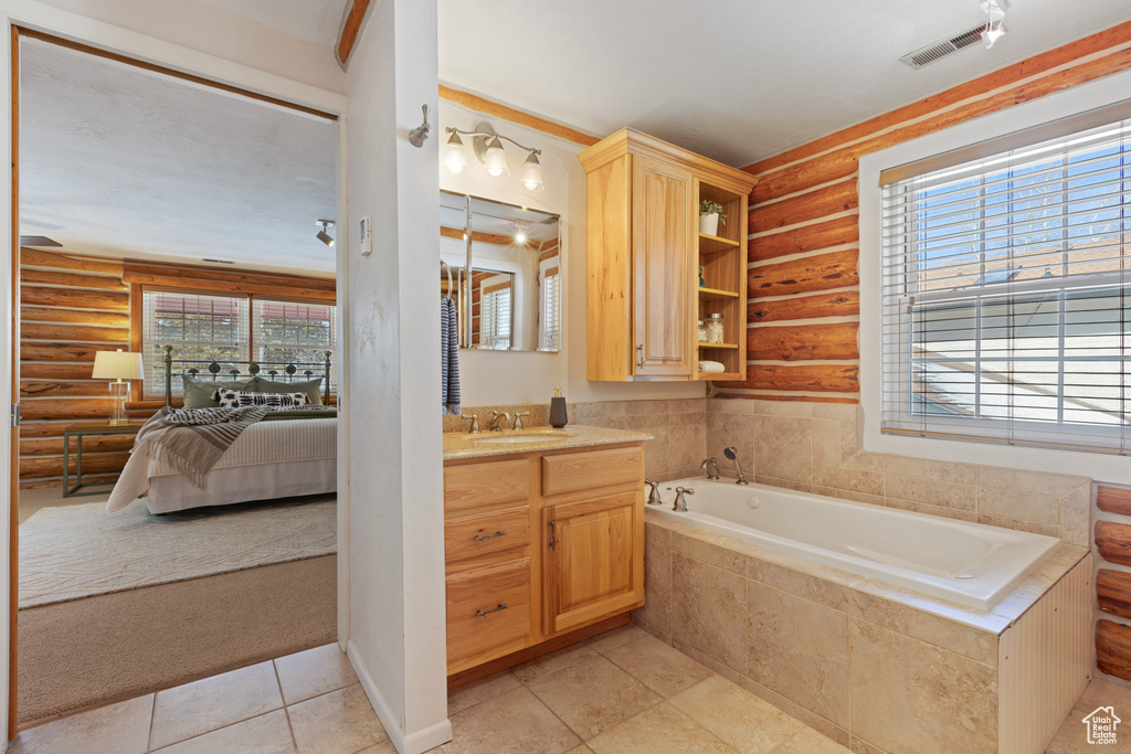 Bathroom featuring tiled bath, log walls, tile floors, and vanity