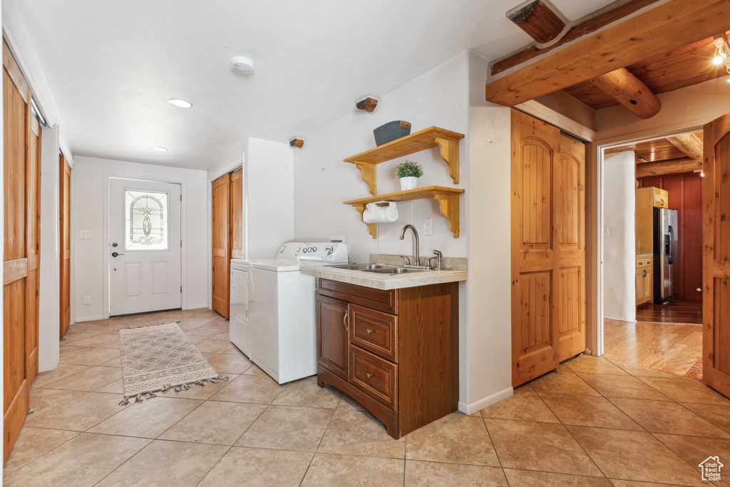 Washroom with cabinets, sink, light wood-type flooring, and washer and clothes dryer
