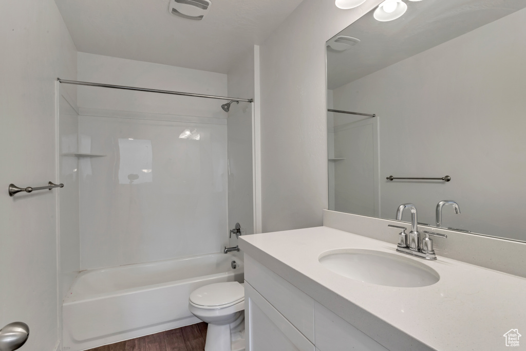 Full bathroom with  shower combination, wood-type flooring, vanity with extensive cabinet space, and toilet