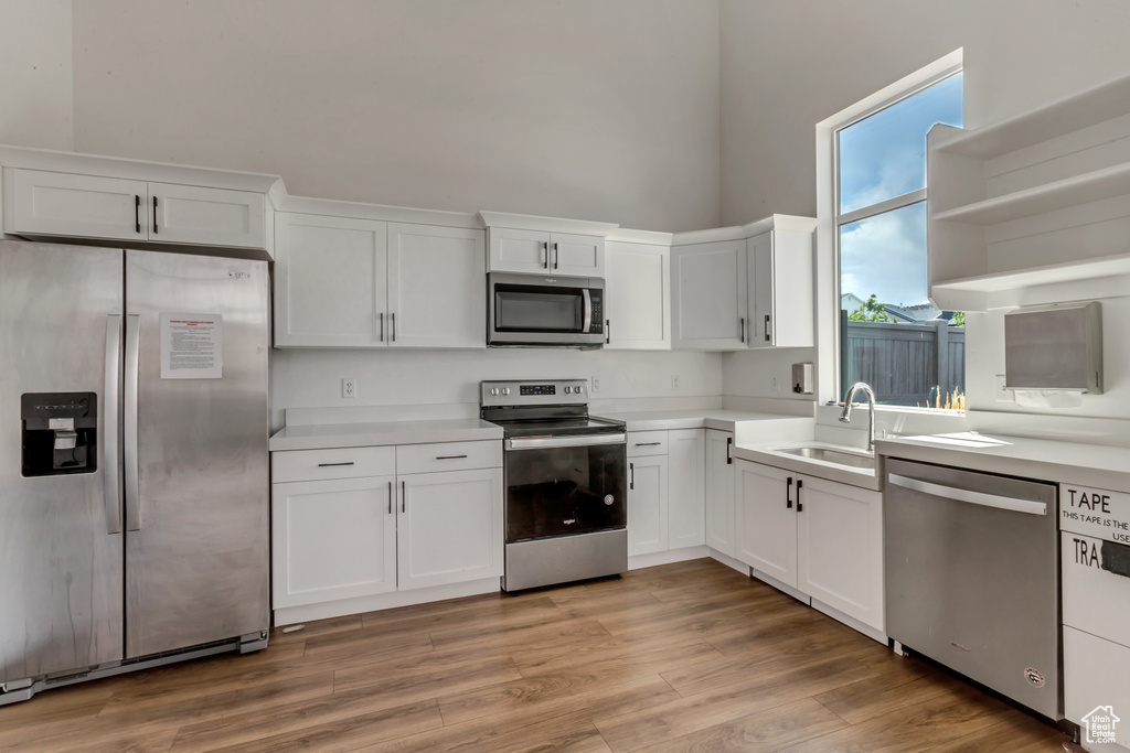 Kitchen featuring appliances with stainless steel finishes, white cabinetry, and light hardwood / wood-style floors