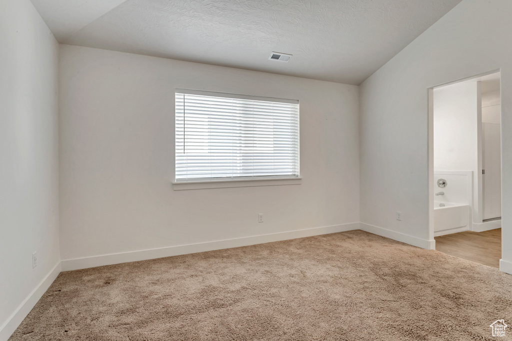 Spare room with light colored carpet and vaulted ceiling