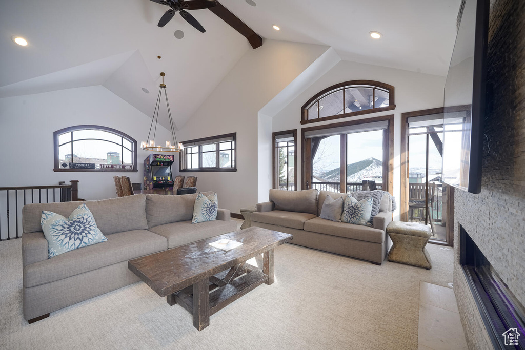 Living room with light carpet, a stone fireplace, ceiling fan, and high vaulted ceiling