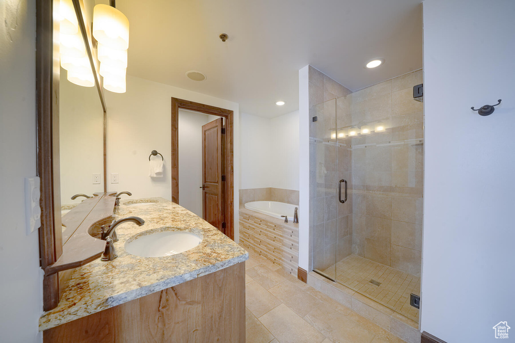 Bathroom featuring shower with separate bathtub, tile flooring, large vanity, and dual sinks