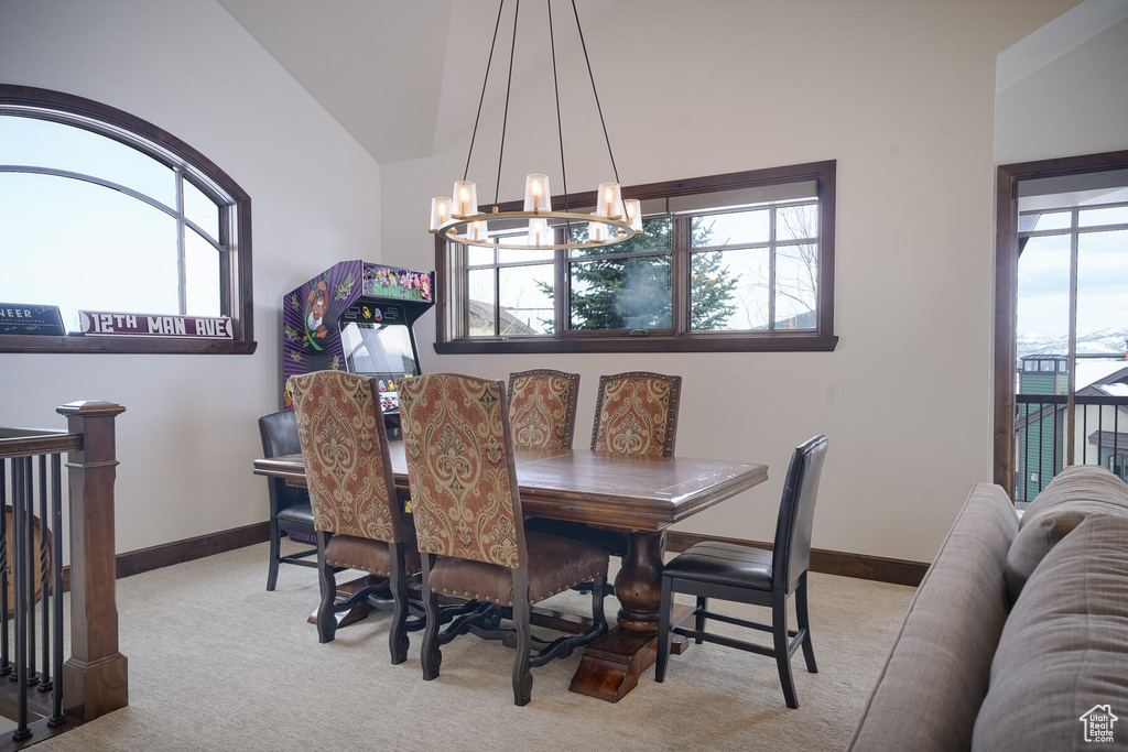 Carpeted dining area featuring lofted ceiling and a notable chandelier