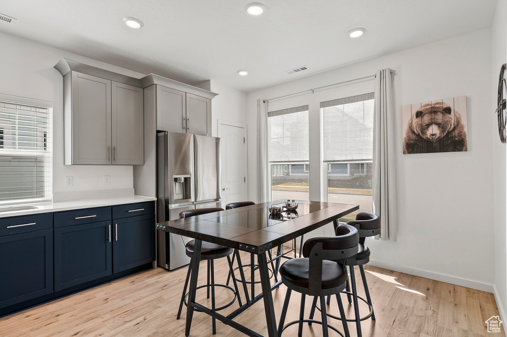 Kitchen featuring gray cabinetry, stainless steel fridge with ice dispenser, and light wood-type flooring