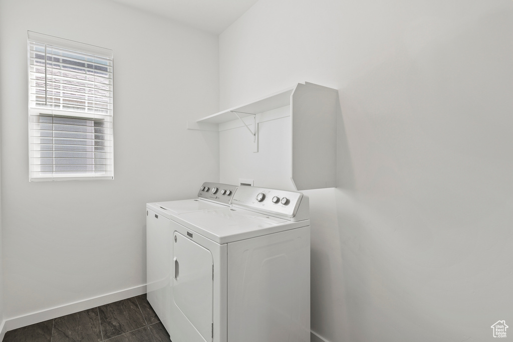 Washroom with dark tile flooring and independent washer and dryer