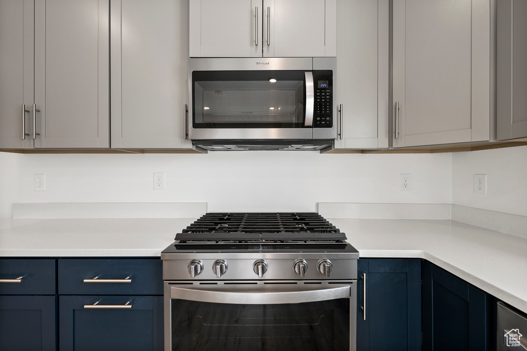 Kitchen featuring gray cabinetry, blue cabinets, and stainless steel appliances