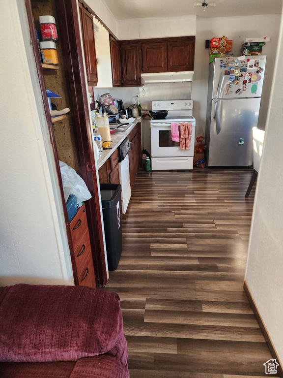 Kitchen featuring dark brown cabinets, white appliances, and dark hardwood / wood-style floors
