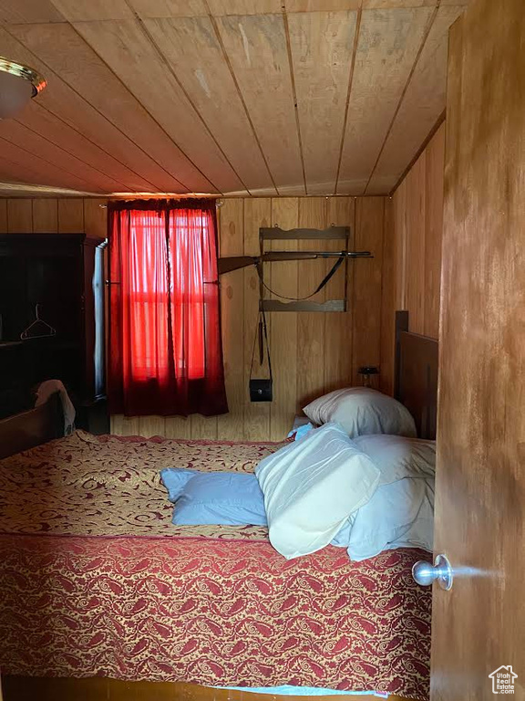 Unfurnished bedroom featuring wooden ceiling and wood walls