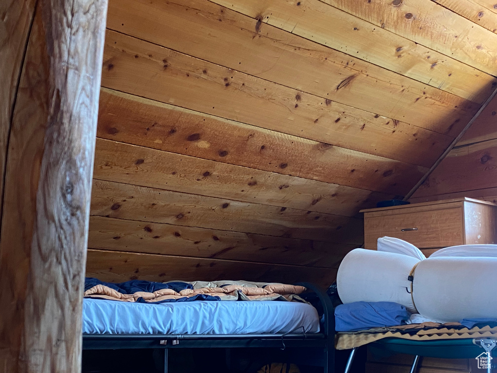 Bedroom with wood ceiling, vaulted ceiling, and wood walls