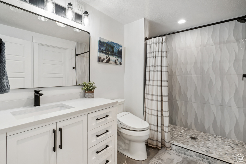 Bathroom featuring toilet, tile flooring, curtained shower, and vanity