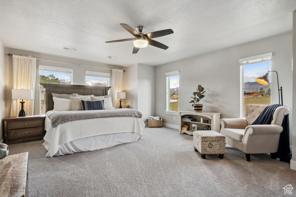 Bedroom with light carpet, a textured ceiling, and ceiling fan