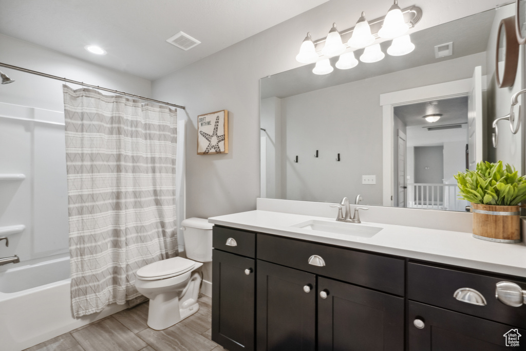 Full bathroom with vanity, shower / bath combo, toilet, and wood-type flooring