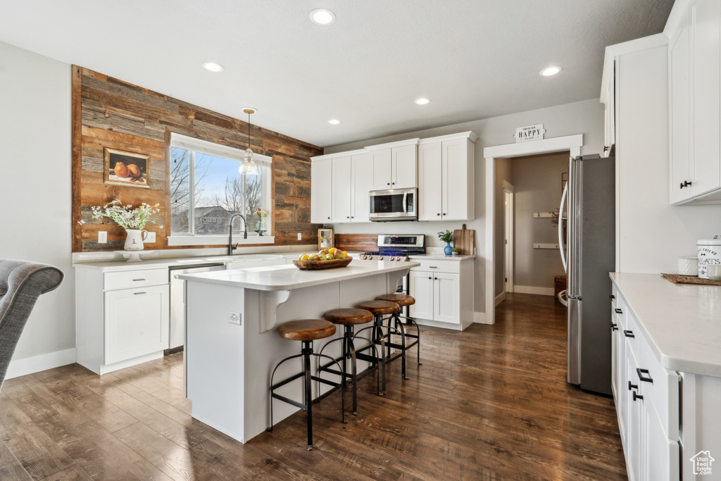 Kitchen with stainless steel appliances, white cabinets, dark hardwood / wood-style flooring, and a center island