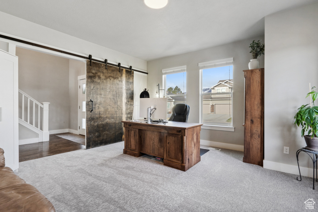 Home office featuring light carpet and a barn door