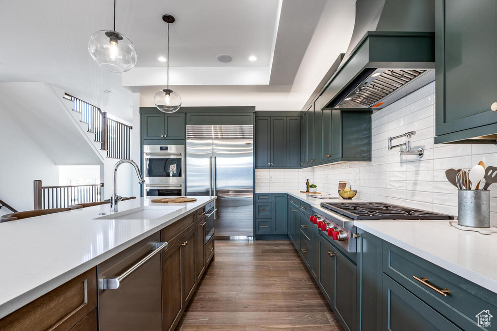Kitchen featuring decorative light fixtures, tasteful backsplash, dark hardwood / wood-style flooring, and wall chimney range hood