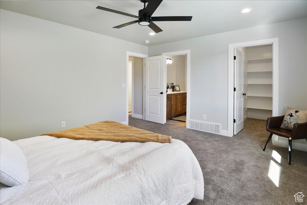 Carpeted bedroom featuring ensuite bathroom, a spacious closet, a closet, and ceiling fan