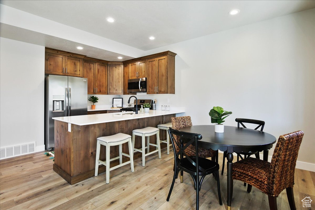 Kitchen featuring kitchen peninsula, sink, a kitchen breakfast bar, stainless steel appliances, and light wood-type flooring