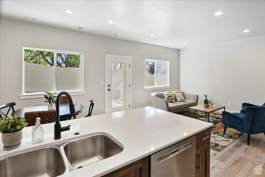 Kitchen featuring a healthy amount of sunlight, light hardwood / wood-style floors, dishwasher, and sink