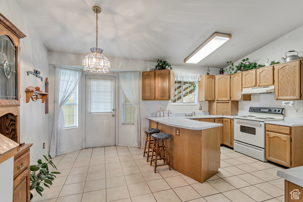 Kitchen featuring a chandelier, pendant lighting, light tile flooring, electric range, and a breakfast bar area