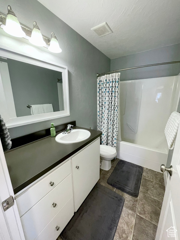 Full bathroom with vanity, tile flooring, toilet, and shower / bathtub combination with curtain