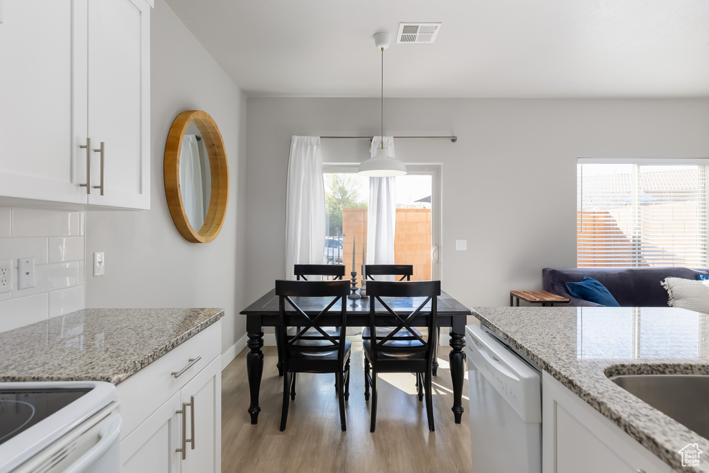 Kitchen featuring hanging light fixtures, light hardwood / wood-style floors, dishwashing machine, and light stone counters