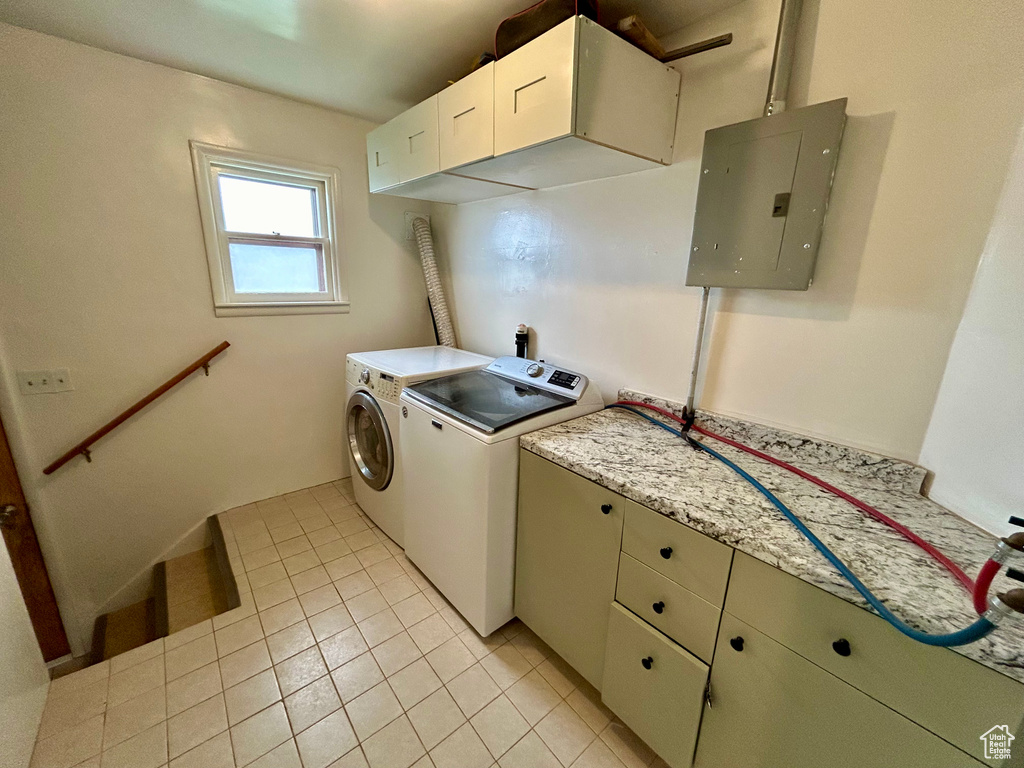 Laundry area with light tile flooring, washing machine and dryer, and cabinets