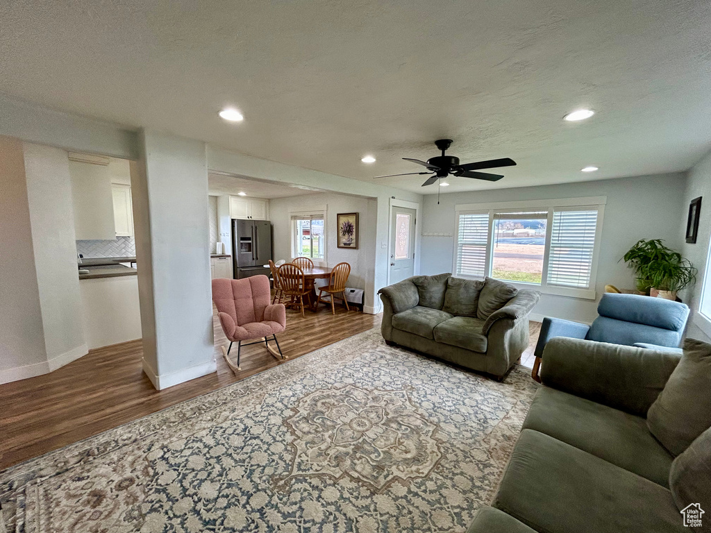 Living room with ceiling fan and hardwood / wood-style flooring