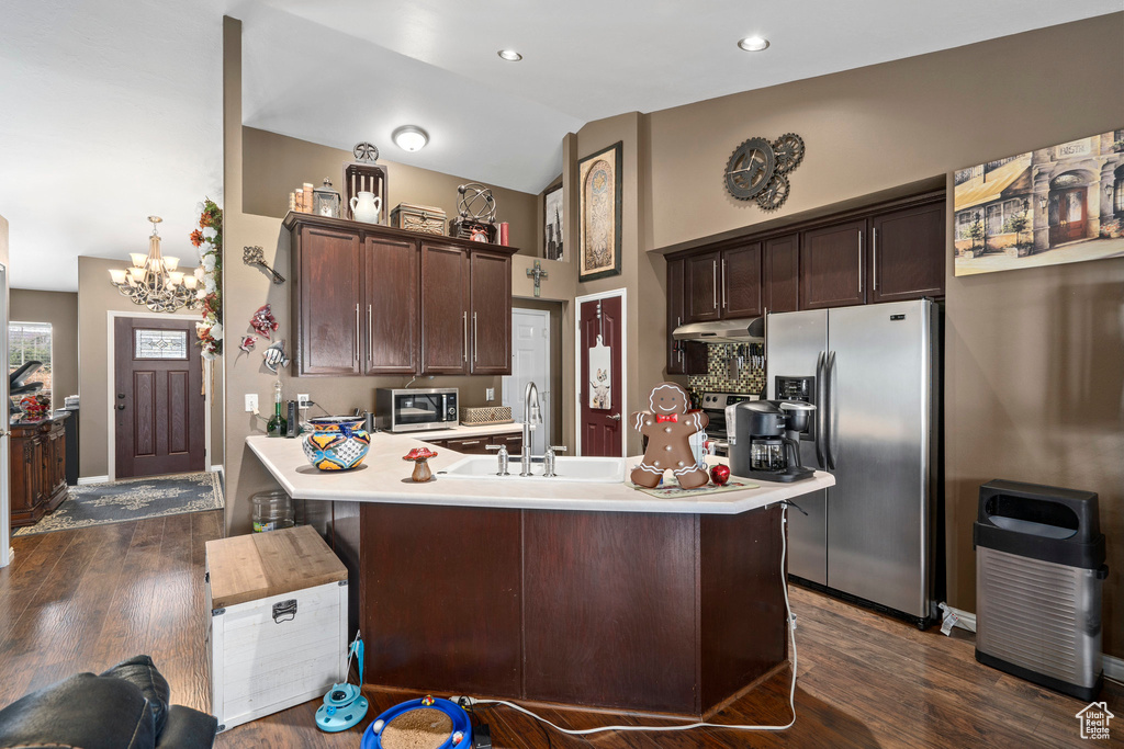 Kitchen with a chandelier, dark brown cabinets, dark wood-type flooring, and appliances with stainless steel finishes