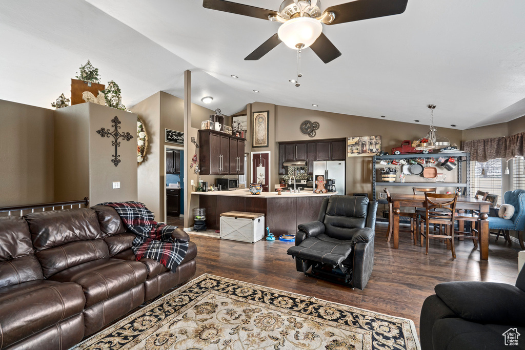 Living room featuring dark hardwood / wood-style floors, ceiling fan with notable chandelier, and vaulted ceiling