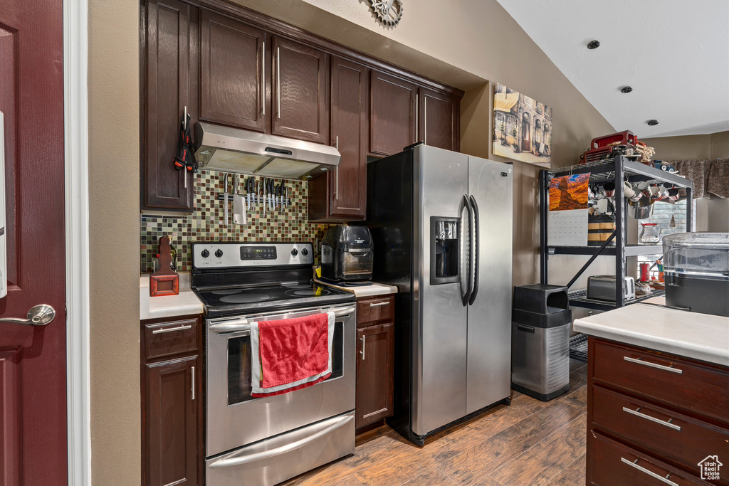Kitchen featuring hardwood / wood-style floors, dark brown cabinets, backsplash, stainless steel appliances, and vaulted ceiling