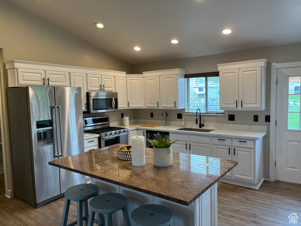 Kitchen with white cabinets, lofted ceiling, sink, and premium appliances