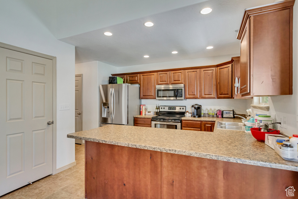 Kitchen featuring appliances with stainless steel finishes, sink, kitchen peninsula, and light tile floors