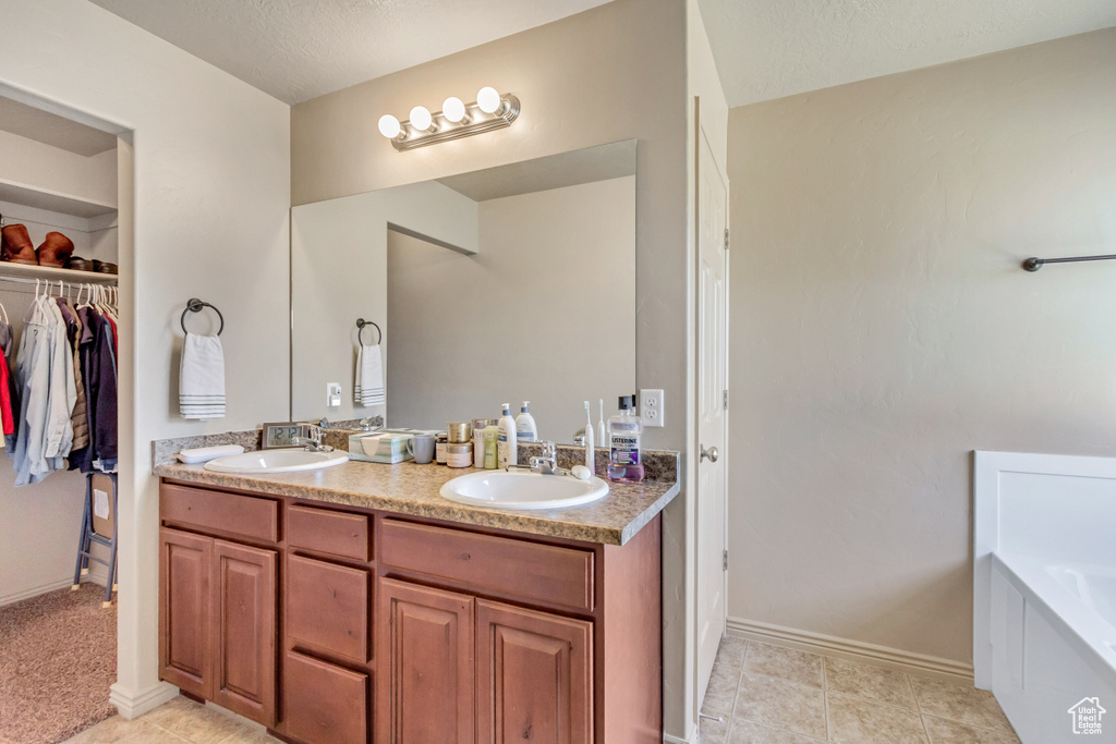 Bathroom featuring a textured ceiling, tile flooring, dual vanity, and a washtub