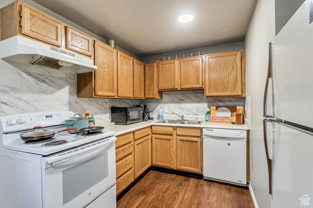 Kitchen featuring white appliances, sink, backsplash, and dark hardwood / wood-style flooring