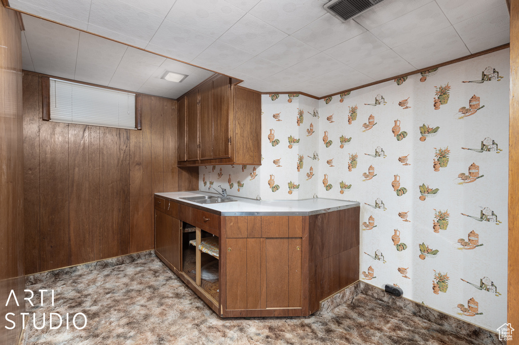 Kitchen featuring sink, light colored carpet, and wood walls