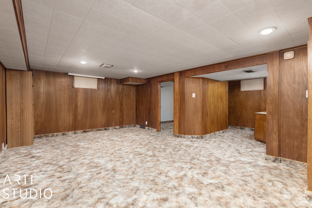 Basement featuring wood walls and light carpet