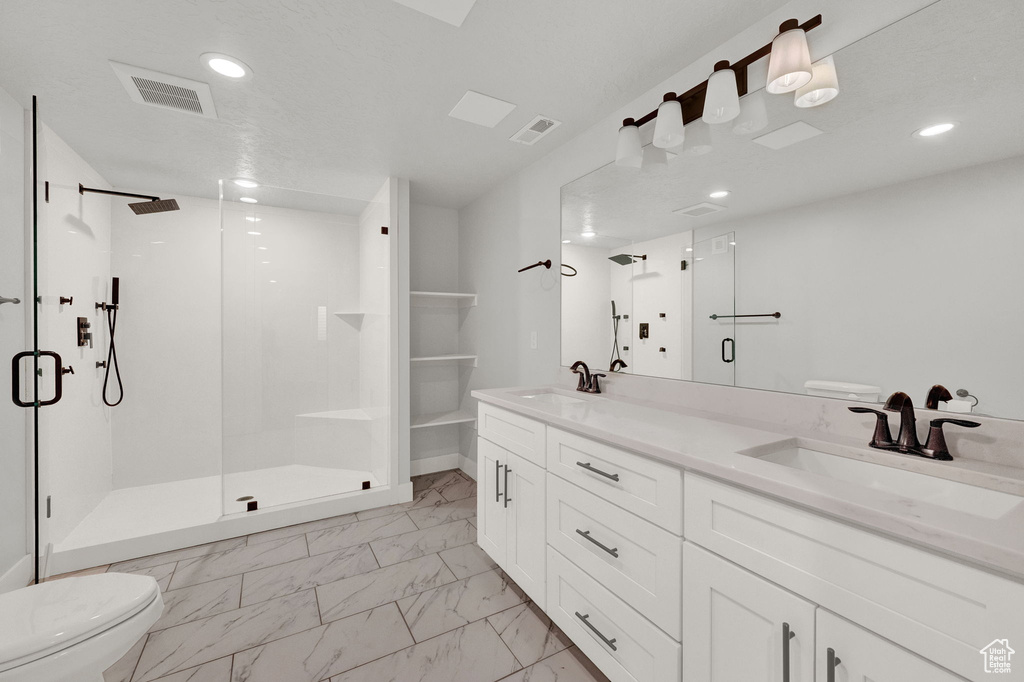 Bathroom with dual vanity, tile flooring, a shower with shower door, and toilet