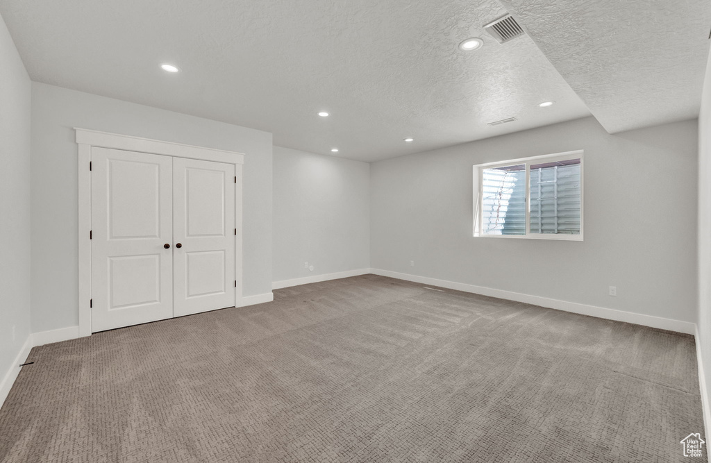 Unfurnished room featuring light carpet and a textured ceiling